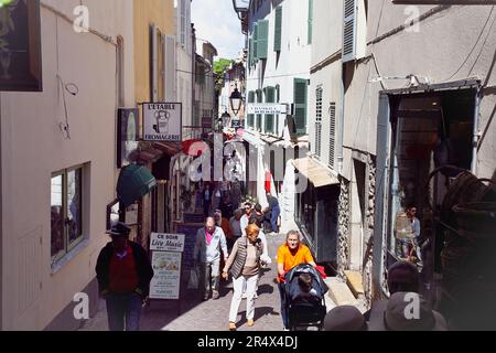 France, Provence-Alpes-Côte d'Azur, Antibes, rue latérale menant au marché provençal animé par les acheteurs. Banque D'Images