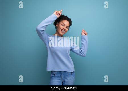 charmante femme brune souriante de 20s avec des boucles afro montrant de la joie Banque D'Images