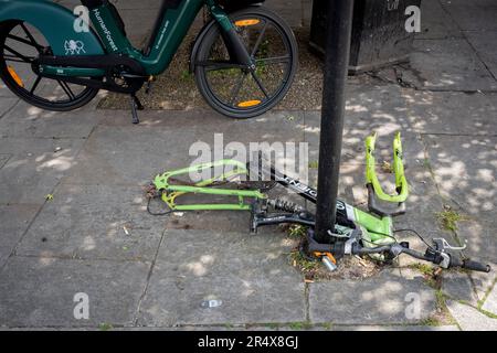 Le cadre d'un vélo dépouillé et abandonné reste verrouillé à un poste à côté d'un vélo de location à Southwark, dans le sud de Londres, le 23rd mai 2023, à Londres, en Angleterre. Banque D'Images