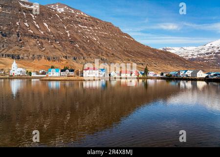 Vue panoramique rapprochée de la ville de Seyðisfjörður (Seydisfjordur) reflétée dans l'eau calme ; Fjords est, Islande est, Islande Banque D'Images