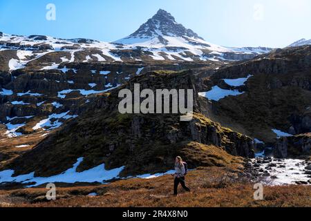 Femme marchant seule le long d'un sentier près d'une rivière ; Islande orientale, Islande Banque D'Images