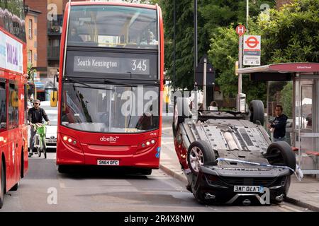 Un bus approche des suites d'un accident de voiture dans lequel un hayon Nissan renversé demeure sur le côté de la route entre Brixton et Camberwell sur Coldport Lane, le 30th mai 2023, à Londres, en Angleterre. Banque D'Images