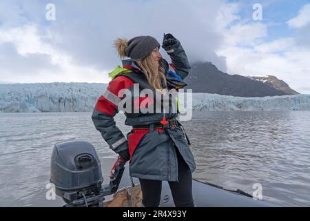 Vue rapprochée d'une femme debout dans un bateau à moteur zodiaque regardant sur l'eau et profitant de la visite en bateau sur la lagune du glacier de Fjallsárlón Banque D'Images