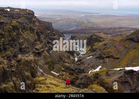 Vue prise de derrière d'une femme debout sur une montagne surplombant une vue de Mulagljufur Canyon, un paradis pour randonneurs, avec une vue imprenable de ... Banque D'Images