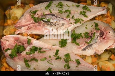 Plat de la préparation d'une recette pour trois moitiés de dorade cuite au four avec légumes et persil Banque D'Images