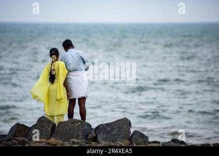 Couple se trouve sur la rive rocheuse de la baie du Bengale ; Puducherry, Tamil Nadu, Inde Banque D'Images