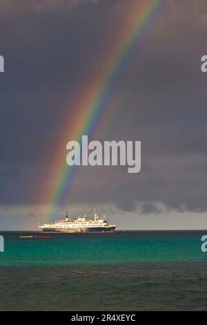 Arc-en-ciel brille au-dessus d'un navire d'expédition de passagers dans les îles Galapagos ; île d'Espanola, îles Galapagos, Équateur Banque D'Images