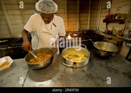 Cuisinier remue une casserole dans la cuisine d'un restaurant en Jamaïque ; Alligator Pond, Jamaïque, Antilles Banque D'Images