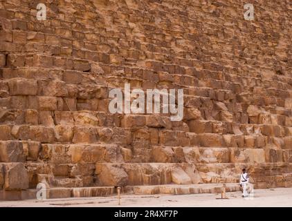 L'homme marche par la base de la Grande Pyramide de Gizeh ; Gizeh, Egypte Banque D'Images