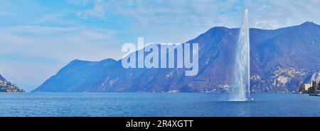 Panorama du lac Crystal Clear de Lugano avec la fontaine Getto d'Acqua (jet d'eau sur la baie de Lugano), les Alpes brumeuses et le Monte Sighignola, Lugano, Tessin, SW Banque D'Images