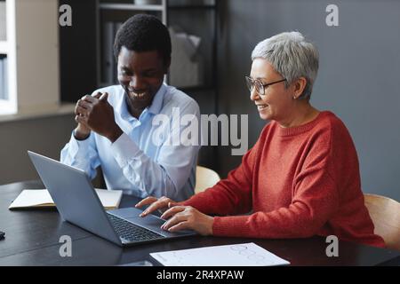 Portrait d'une femme d'affaires souriante utilisant un ordinateur portable avec un collègue sur le lieu de travail au bureau Banque D'Images