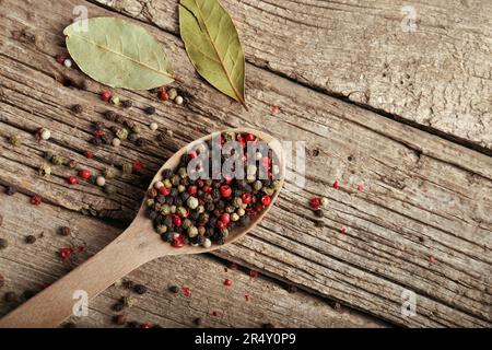 Mélanger les poivrons et les pois dans une cuillère en bois sur fond de bois, vue du dessus. Poivron rouge, poivre blanc et poivre vert. Banque D'Images