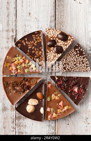 Composition créative chocolat sous forme de pizza aux fruits confits, noix, baies sèches, pizza au chocolat et ingrédients sur fond de bois. Banque D'Images