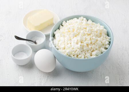 Ingrédients : fromage cottage, œuf, beurre, sel, soda pour cuisiner du fromage fondu maison sur fond gris clair. Banque D'Images