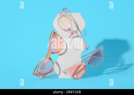 Podiums avec différentes lunettes de soleil stylées sur fond bleu Banque D'Images