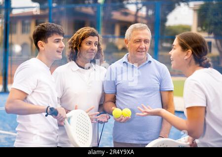 Quatre joueurs de paddle-tennis qui parlent sur le court Banque D'Images