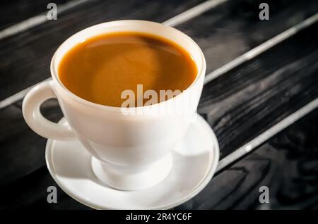 Café chaud dans une tasse. Café dans la tasse sur une table en bois noir. Photo avec une faible profondeur de champ. Banque D'Images