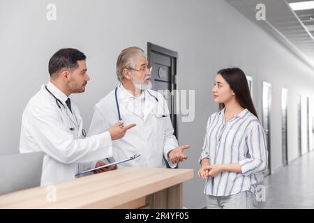 Médecins consultant le patient près de la réception dans le hall de la clinique Banque D'Images