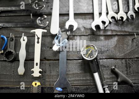 Clés et autres pièces de fixation accrochées à un tableau d'outillage dans un atelier de réparation de bicyclettes. Vue frontale rapprochée. Banque D'Images