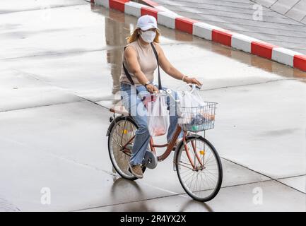 SAMUT PRAKAN, THAÏLANDE, MAI 10 2023, Une femme à vélo dans la rue des pluies. Banque D'Images