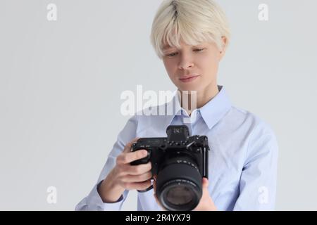 Femme blonde aux poils courts règle l'appareil photo numérique Banque D'Images