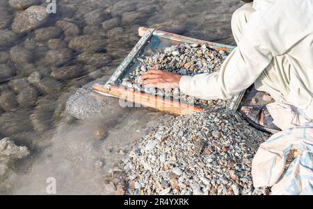 Homme lavant et rinçant les graviers de la mine d'émeraude Swat dans l'espoir de trouver quelques pièces de pierre gemmes émeraude Banque D'Images