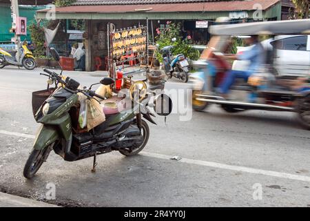 SAMUT PRAKAN, THAÏLANDE, MARS 24 2023, le calmar sec pressé pendent d'un support monté sur la moto d'un vendeur de rue Banque D'Images