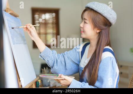 Jeune femme artiste création de dessin et peinture d'œuvres d'art sur toile avec plaisir dans le studio à la maison. Banque D'Images