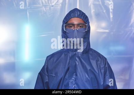Portrait à la taille de l'homme scientifique portant une combinaison de protection complète en laboratoire ou à l'hôpital et regardant l'appareil photo sur le masque Banque D'Images