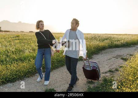 Un jeune couple épris inspiré regarde le plan de vie à l'avenir. Ils sont debout avec une valise et ukulele, tenant les mains. Recherche d'une nouvelle patrie. Banque D'Images