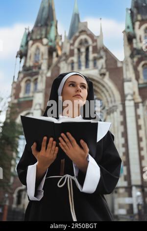 Jeune nonne lisant la Bible près de la cathédrale en plein air Banque D'Images