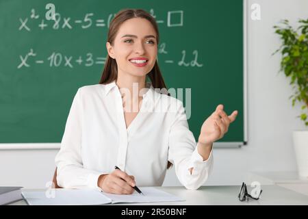 Un jeune professeur de mathématiques donne une leçon à table en classe Banque D'Images