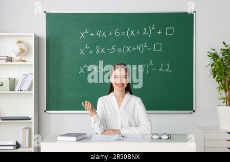 Un jeune professeur de mathématiques donne une leçon à table en classe Banque D'Images