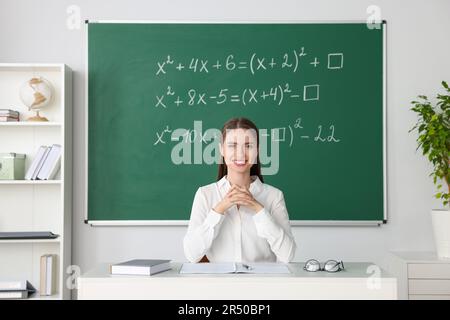 Un jeune professeur de mathématiques donne une leçon à table en classe Banque D'Images