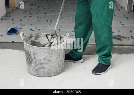 Homme mélangeant de l'adhésif pour carreaux à l'intérieur, vue rapprochée Banque D'Images