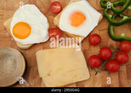 Toasts savoureux avec œufs frits, fromage et légumes sur bois, plat Banque D'Images