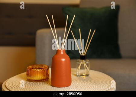 Désodorisants aromatiques en roseau et bougie parfumée sur table à l'intérieur Banque D'Images