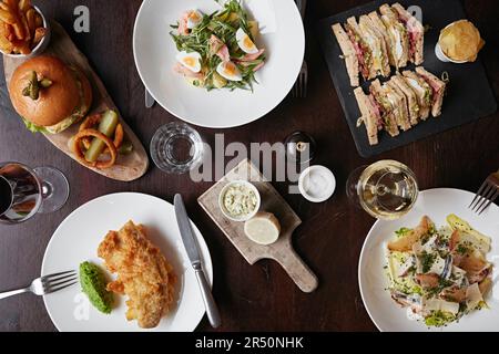 Sélection de plats pour le déjeuner disposés sur une table avec vin et couverts Banque D'Images