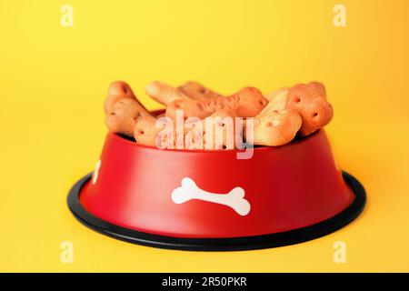 Biscuits pour chiens en forme d'os dans un bol sur fond jaune Banque D'Images