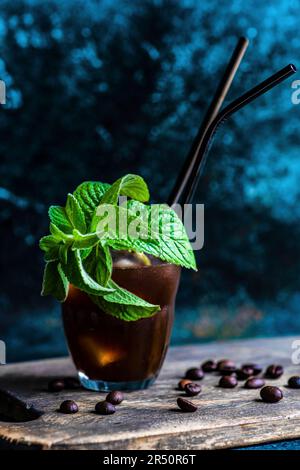 Café fouetté mousseux cocktail russe blanc servi dans le verre et décoré de grains de café et de feuilles de menthe fraîche Banque D'Images