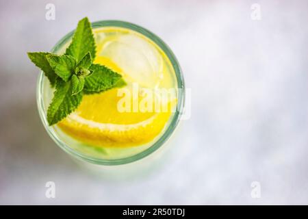Cocktail Mojito à la menthe et au citron, servi dans un verre de cristal sur une table en béton Banque D'Images
