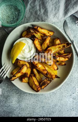 Pommes de terre croustillantes et sauce à la crème sure avec ail et fines herbes servies dans le bol sur fond de béton gris Banque D'Images