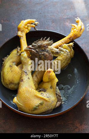 Poulet avec tête et pieds dans une casserole Banque D'Images