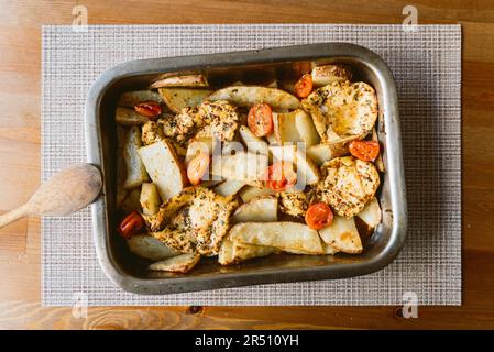 poulet au four maison avec pommes de terre et tomates sur une table en bois sur un plateau en aluminium poulet mariné cuit au four pour le rôti du dimanche Banque D'Images