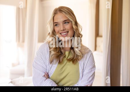 Portrait d'une jeune femme caucasienne de taille plus belle avec les bras croisés souriant et regardant loin Banque D'Images