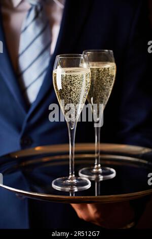 Un barman servant deux verres de champagne Banque D'Images