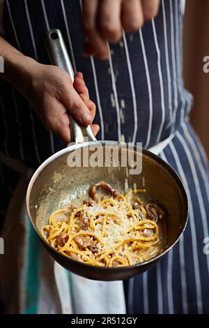 Un chef saupoudrer de parmesan sur des pâtes Banque D'Images