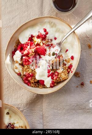 Barres d'avoine friable avec grenade et graines de citrouille servies avec yaourt blanc et framboises Banque D'Images