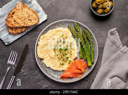 Photographie de nourriture de petit déjeuner, œufs brouillés, brunch, omelette, saumon fumé, asperges, olives, toasts Banque D'Images