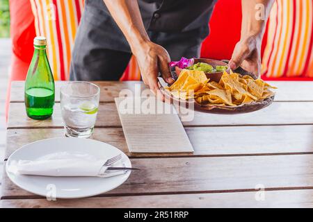 Serveur servant des chips de nachos mexicaines, sauce guacamole. Banque D'Images